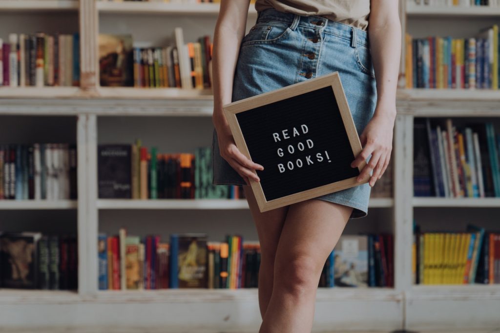 girl holding sign saying "read good books"